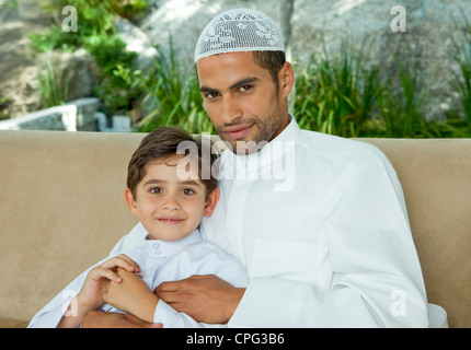 Portrait of an arab father and son sitting on sofa. Stock Photo