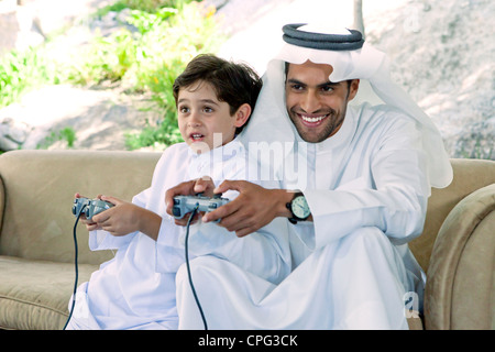 Arab father and son playing video game together. Stock Photo