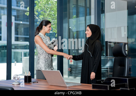 Two businesswomen shaking hands in office. Stock Photo