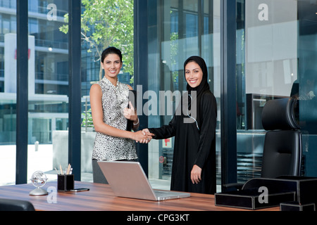 Two businesswomen shaking hands in office. Stock Photo