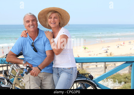 Mature couple with bikes by the beach Stock Photo