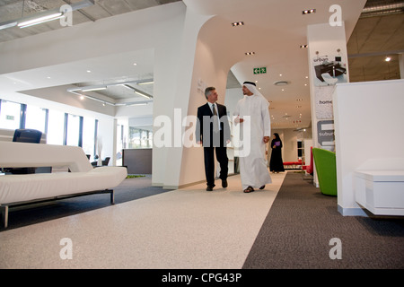 Two businessmen talking while walking in the office hallway. Stock Photo