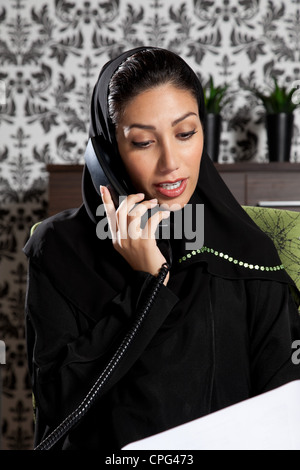 Arab businesswoman on telephone, holding a document on her desk. Stock Photo