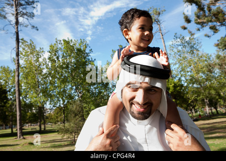 Arab father with son sitting on shoulders at the park. Stock Photo