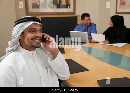 Businessman using mobile phone, two colleagues in background. Stock Photo