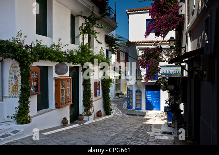 Shops and tavernas in a narrow alleyway in the old part of Skiathos Town Stock Photo