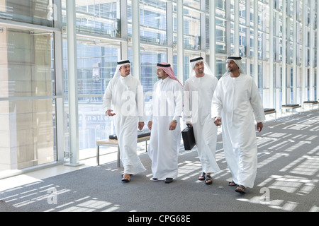 Four arab businessmen talking while talking in the office hallway. Stock Photo