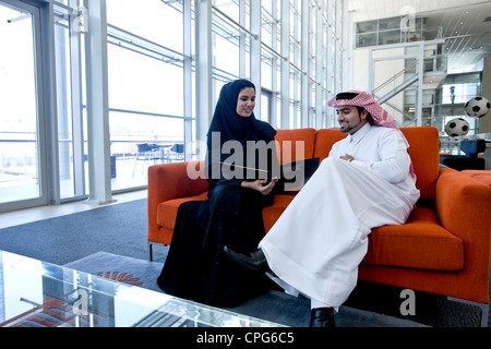 Arab businessman and businesswoman discussing a document in sofa. Stock Photo