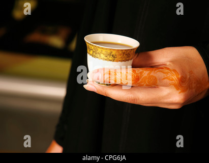 Arab lady with henna on hands holding Arabic Coffee cup Stock Photo