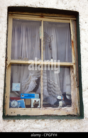 Window of an empty house with stickers on the glass and things left on the window ledge Stock Photo