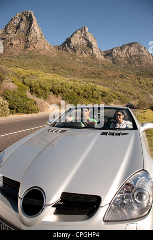 Couple riding in a convertible car, smiling. Stock Photo