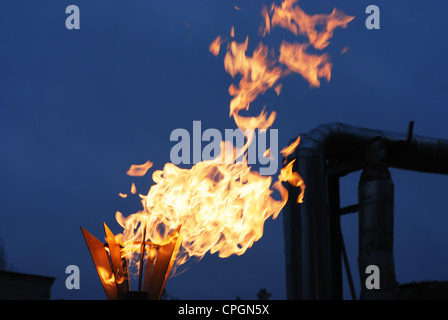 burning torch against industrial dusk background Stock Photo