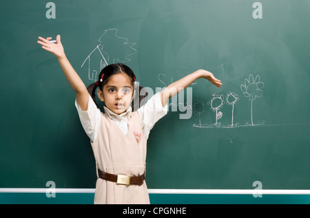 Girl (6-7) standing by board, arms raised Stock Photo