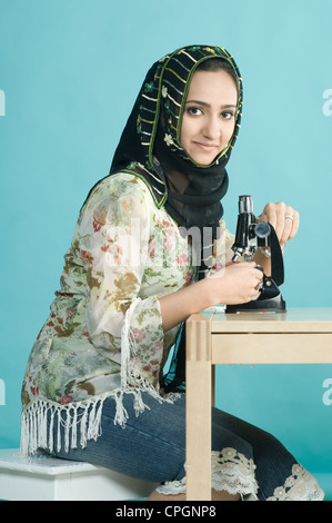 Woman sitting with microscope, portrait Stock Photo