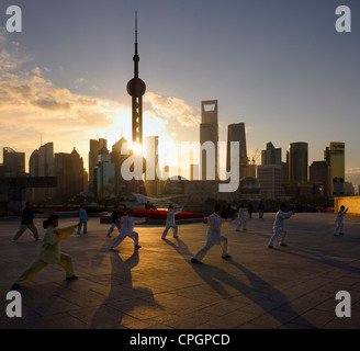 Sunrise shining through the Oriental Pearl Tower onto Tai Chi group exercising on the Bund Shanghai China Stock Photo