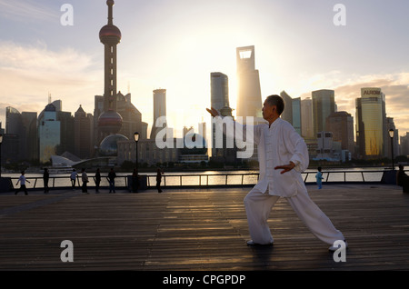 Man in white uniform doing Tai Chi exercises on the Bund at dawn with Shanghai financial towers Peoples Republic of China Stock Photo