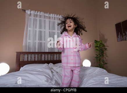 Girl (3-4) jumping on bed Stock Photo