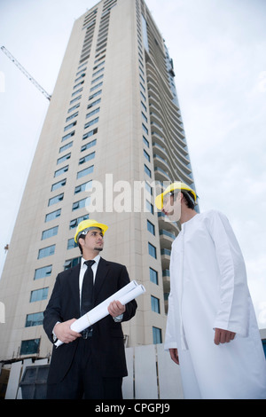 Businessmen holding blueprint looking at each other Stock Photo