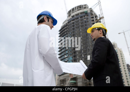 Businessmen with blueprints looking at each other, low angle view Stock Photo
