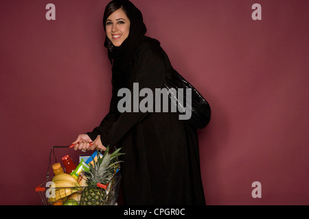 Young woman holding shopping cart, portrait Stock Photo