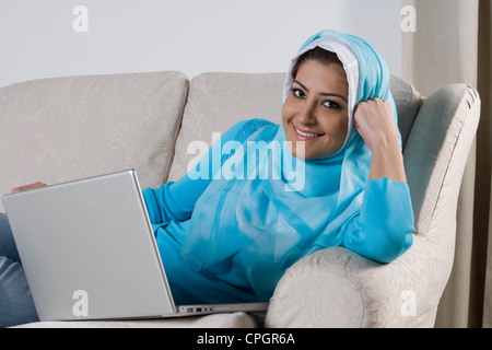 Young woman lying on sofa with laptop, portrait Stock Photo
