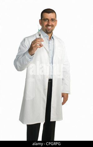 Doctor holding syringe standing against white background, smiling, portrait Stock Photo