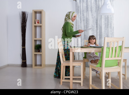 Arab mother and daughter in the dining room, woman setting table Stock Photo