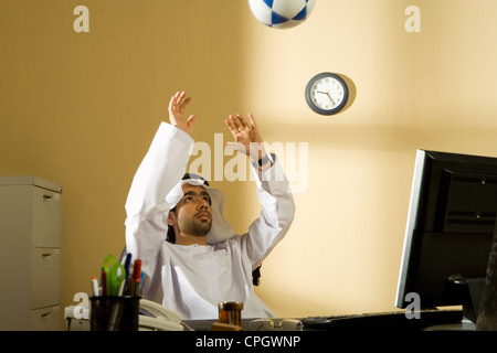 Arab man playing football in office Stock Photo