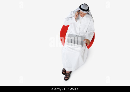 Young man on the phone, using laptop, elevated view Stock Photo