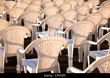 Plastic chairs waiting for an evening performance form a geometric pattern in the sunlight Stock Photo