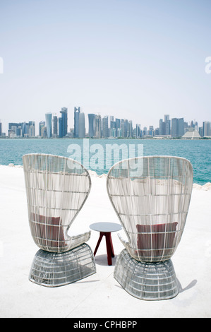 Modern outdoor seating at waterfront cafe with view of skyline of Doha in qater Stock Photo