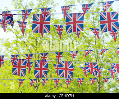 Union Jack flag bunting in front of sunlit trees Stock Photo