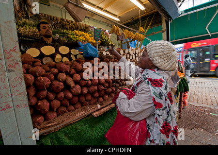 Woman shopping for fresh vegetables in Lewisham Market South London Stock Photo