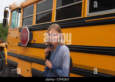 Middle school student smiling in front of her school bus. Stock Photo