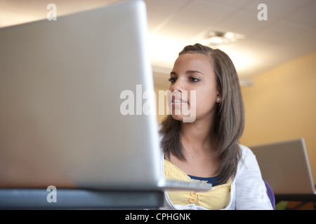 African American teenager using a laptop computer to work in the classroom. Stock Photo