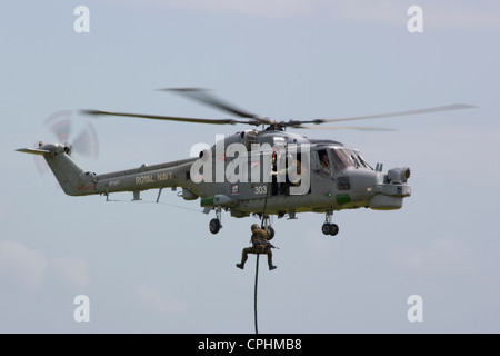 Commando with machine gun absailing from a Royal Navy Agusta Westland Lynx helicopter Stock Photo