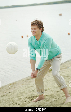 Photo of handsome man playing volleyball on the beach Stock Photo