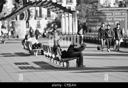 BARCELONA, SPAIN - DECEMBER 2011 : Rasta sitted on a bench on Colom sea shore. Stock Photo