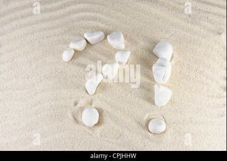 Question and exclamation mark arranged by stones with sand background Stock Photo