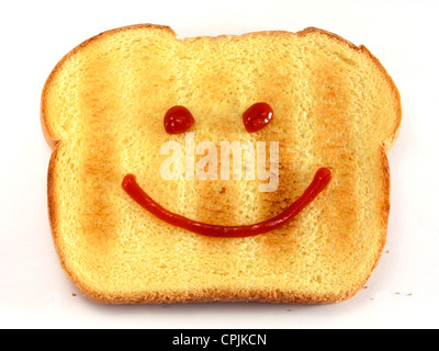 Single piece of toasted bread with a drawn happy face isolated on white background. Stock Photo