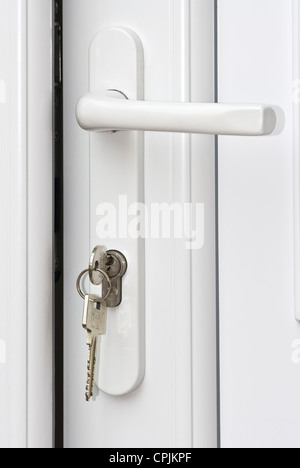 Keys unlocking a white Upvc door. Stock Photo