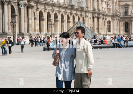 Paris, France - Japanese tourist couple being photographed in front of the Louvre museum. Stock Photo