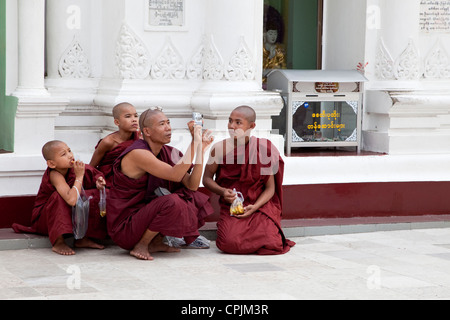 Myanmar, Burma. Shwedagon Pagoda, Yangon, Rangoon. Buddhist Monk Photographing the Stupa. Monks can be tourists too. Stock Photo