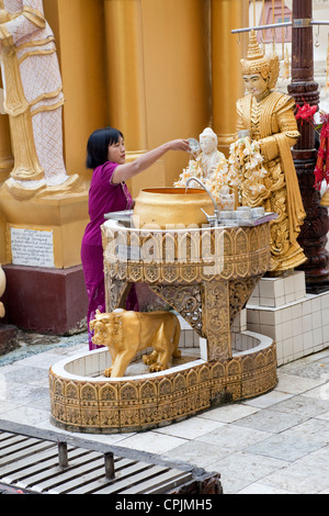 In a Purifying Ritual, Woman Pours Water on a Nat, a Mythical Buddhist Spirit Worshiped in Myanmar.   Shwedagon Pagoda, Yangon. Stock Photo
