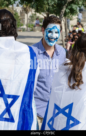 Young man with an Israeli flag painted on his face pausing with people. Jerusalem. Israel. Stock Photo