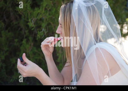 Bride putting on lip gloss before her wedding ceremony. Stock Photo
