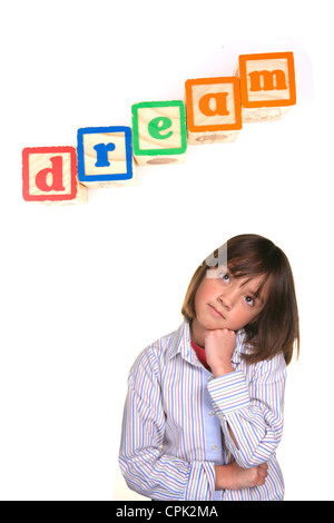 A young girl in a dreaming posture with the word dream above in blocks. Stock Photo