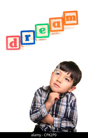 A young boy in a day dreaming pose under the word blocks. Stock Photo