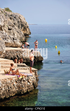 Bathers on rocky ledges, Cala en Forcat, Menorca, Balearic Islands, Spain Stock Photo