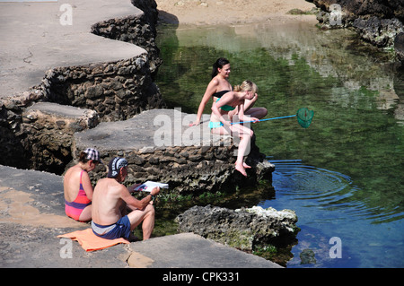 Bathers on rocky ledges, Cala en Forcat, Menorca, Balearic Islands, Spain Stock Photo